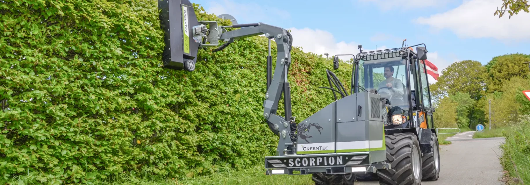 Front mounted arm mower cuts hedges